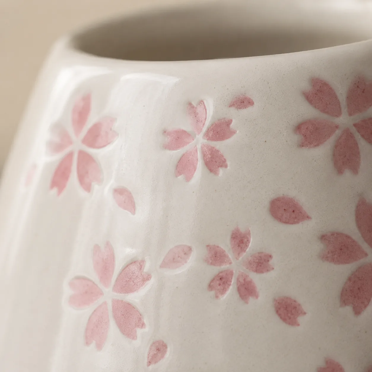 Close-up of a cream glazed ceramic whisk holder hand-painted with soft pink cherry blossom petals