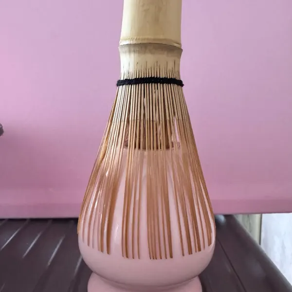 Pink ceramic matcha whisk holder photographed by a buyer against a pink wall