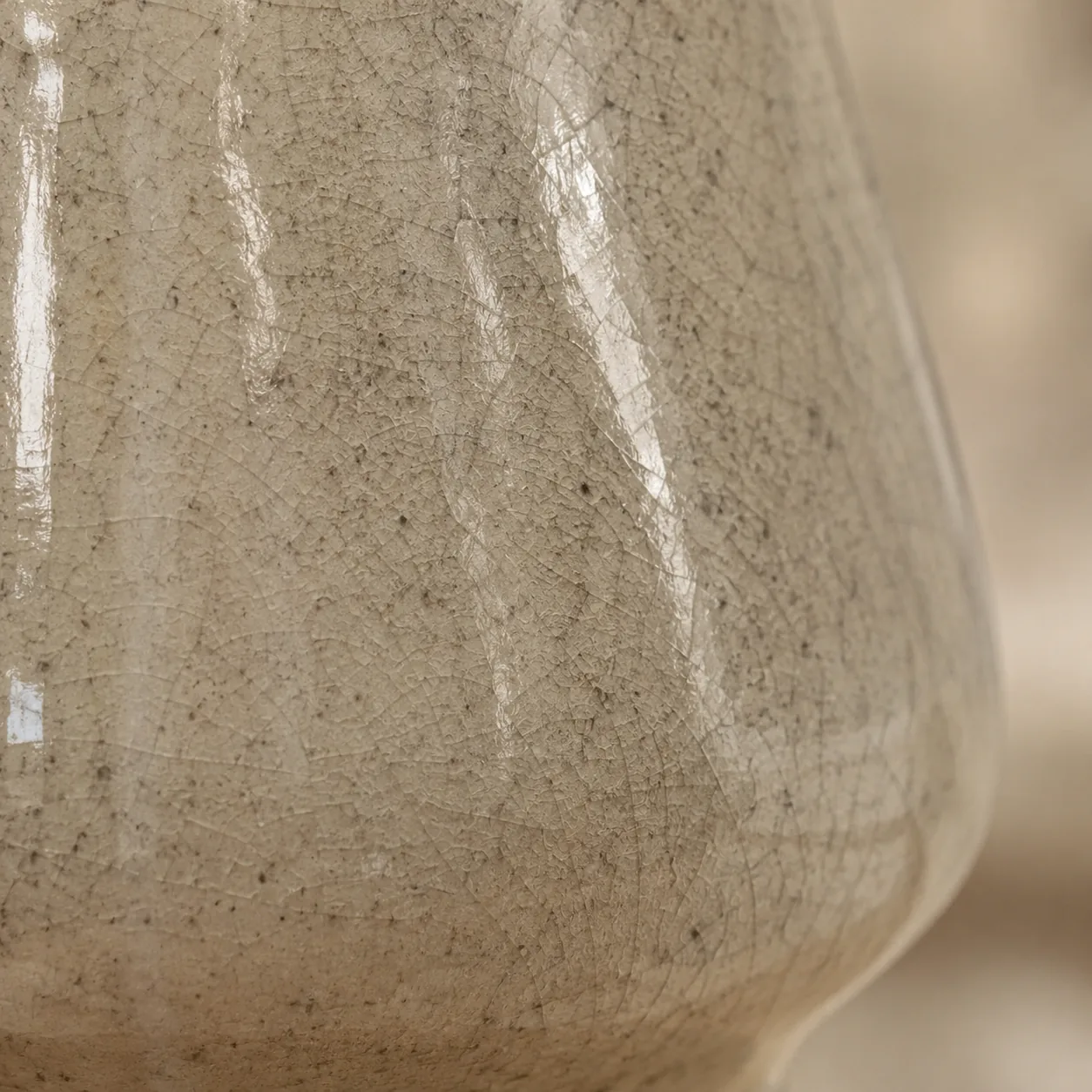 Macro close-up of the holder's glossy cream ceramic glaze, its fine crackle finish and sealed surface shedding water rather than soaking it up